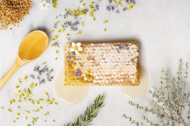 Pot de mel natural d'Avi Lluís amb fons rústic, simbolitzant els beneficis ancestrals de la mel.